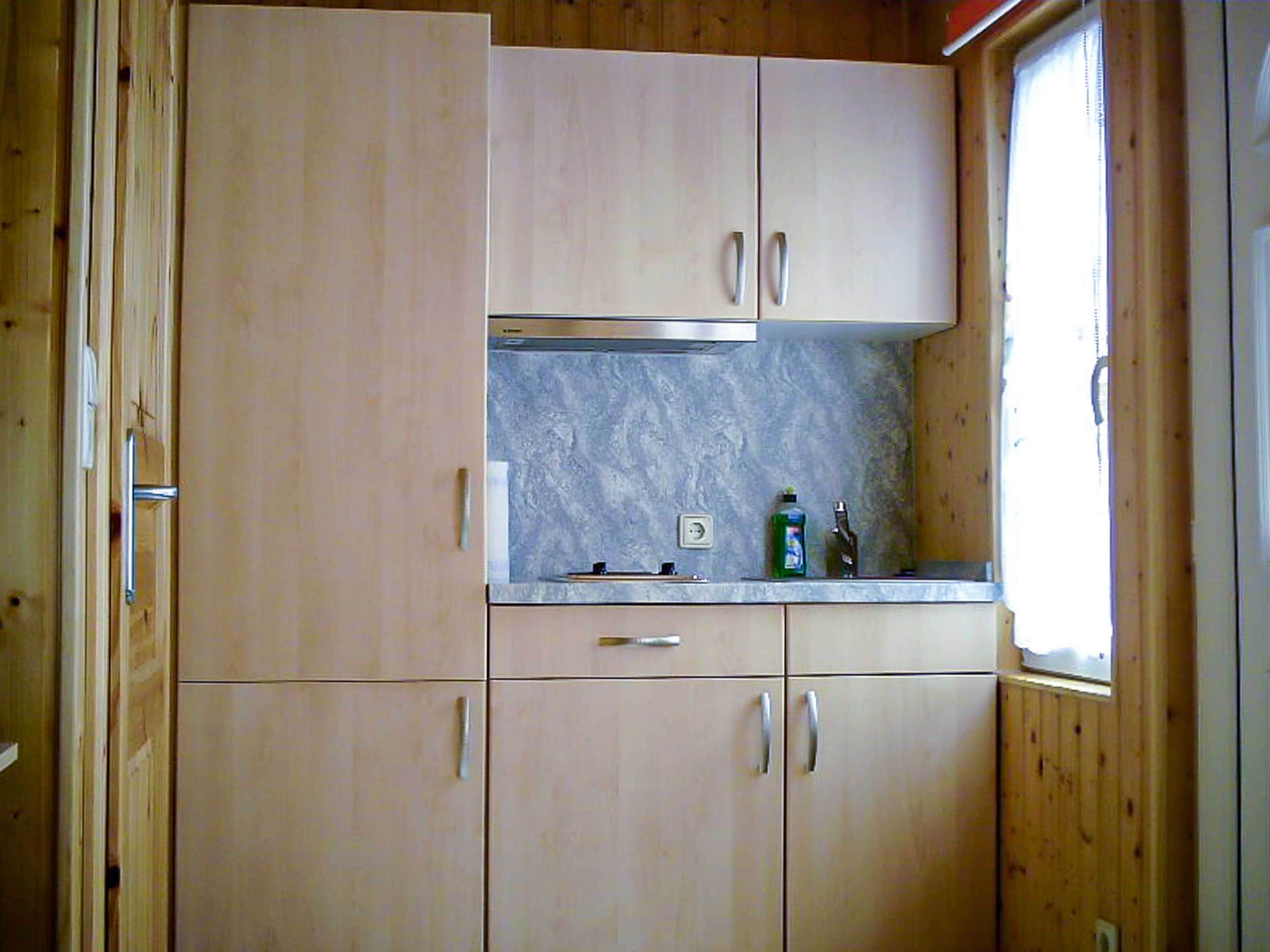 Eine Küche mit Holzausstattung, einer Marmorarbeitsplatte und einem Fenster.
