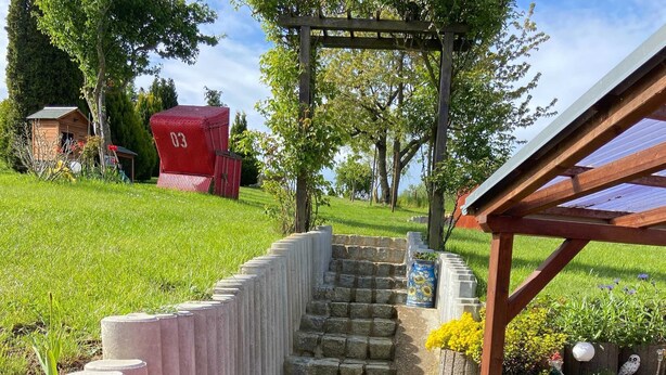 A stone staircase leading to a wooden pergola with a garden area.