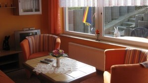 A living room with a sofa, a table with a vase of flowers, a cabinet, and a window with a view of the outside.