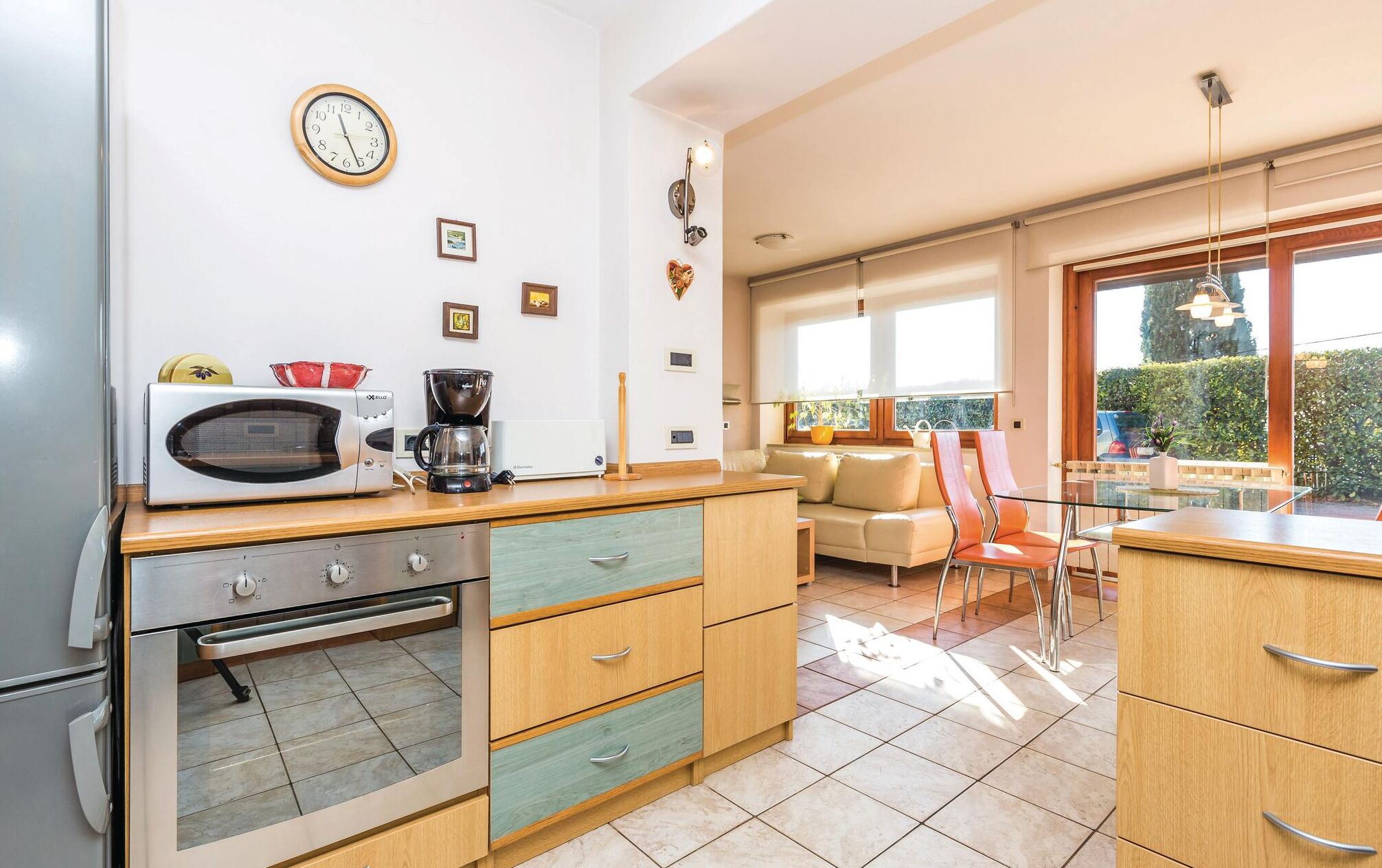 A modern kitchen with a microwave, coffee maker, and oven. There is a dining area with a table and chairs, and a large window providing a view of the outdoors.
