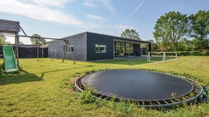 Una casa moderna con un trampolino in giardino, un'altalena e un pallone da calcio.