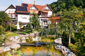 Ein Hotel mit Teich, umgeben von Grünflächen und einem Gebäude mit rotem Dach.