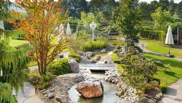 A garden with a pond, rocks, and a wooden bridge.