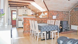 Una zona pranzo accogliente mansardata, con parete in mattoni, travi in legno al soffitto e tavolo apparecchiato per quattro persone.