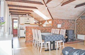 Cozy attic-style room with a dining area, brick fireplace, kitchenette, and large window.