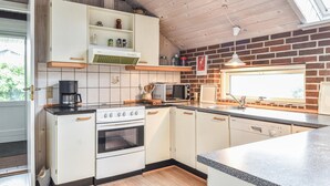 Una cucina compatta con mobili bianchi, forno integrato, microonde e macchina da caffè.