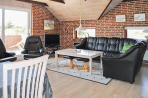 Relax in this stylish living room with a brick wall, leather sofa, and flat-screen TV.