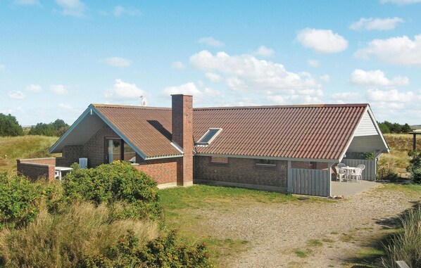 A two-story house with a sloped roof, a chimney, and a small attached garage. - Amazing home in Ringkøbing with sauna (Ringkøbing)