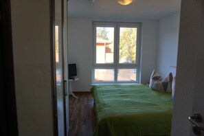 Une chambre à coucher avec un lit, une fenêtre et un téléviseur posé sur un meuble.