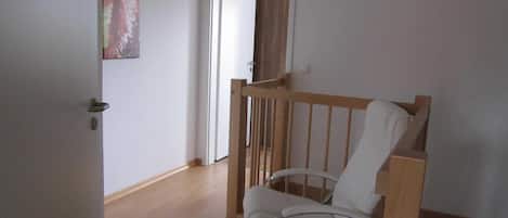 A room with a wooden chair, a door, and a wall-mounted picture.