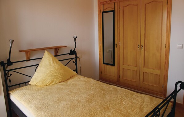 A single bed with a yellow pillow and a wooden shelf above it, a wardrobe with a mirror, and a wall socket. - 3 bedroom amazing home in Monnegre (Monnegre)