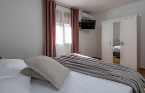 A bedroom with a bed, a wardrobe, and a television mounted on the wall. - Beautiful home in Krvavici (Krvavici)