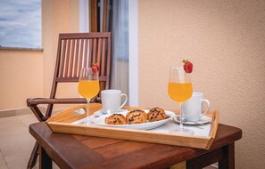 A wooden table with a tray holding a plate of croissants, two white cups, two glasses of orange juice, and a wooden chair. - Beautiful home in Krvavici (Krvavici)