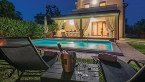 Ein modernes Haus mit Swimmingpool, Sitzgelegenheiten im Freien und einer überdachten Terrasse.