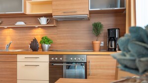 Una cocina moderna con armarios de madera, horno empotrado, cafetera y plantas decorativas.