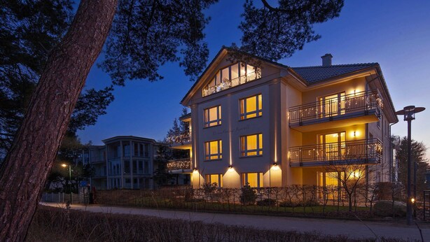 Un hotel de varios pisos con balcones, ventanas amplias y una fachada bien iluminada.