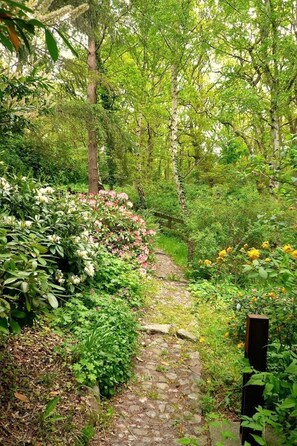 Un sendero de piedra bordeado de exuberante follaje y plantas florecientes.