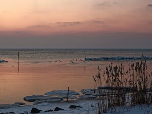 A coastal scene with ice formations, a calm sea, and a clear sky. - House Incognito, Germany (Sellin)