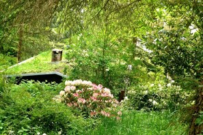 A lush garden with a brick structure, dense foliage, and flowering plants. - House Incognito, Germany (Sellin)