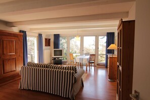 A living room with a striped sofa, a TV, a dining table with chairs, and a wooden cabinet. - House Incognito, Germany (Sellin)