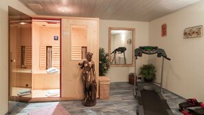 Ein Raum mit einer Holzsauna, einer Statue, einem Laufband und einem Spiegel.