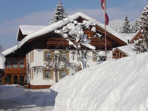 A snow-covered lodge with a wooden facade, large windows, and a flag.