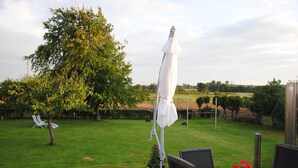 A patio area with a table and chairs, a white umbrella, and a tree. - Vacation apartment in Wackerballig/Gelting 200m to the beach - Holiday apartment (Gelting)