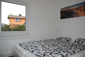 Un dormitorio con cama, ventana e imagen colgada en la pared.