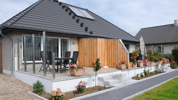 A modern house with a covered patio, outdoor seating, and a variety of potted plants. - Vacation apartment in Wackerballig/Gelting 200m to the beach - Holiday apartment (Gelting)