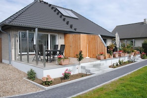 A modern house with a covered patio, outdoor seating, and a variety of potted plants. - Vacation apartment in Wackerballig/Gelting 200m to the beach - Holiday apartment (Gelting)