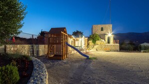 A playground with a slide and climbing structure, surrounded by stone walls and a stone building with a tower. - Stunning apartment in Split (Split)