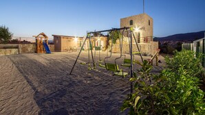 A playground with swings and a slide, a stone tower, and a building with a balcony. - Stunning apartment in Split (Split)
