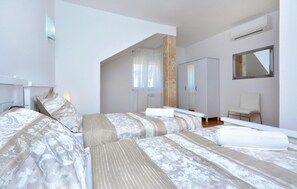 Une chambre moderne avec deux lits, un grand miroir et une armoire.