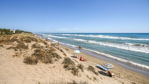A beach with sand dunes, beach umbrellas, and people enjoying the seaside. - Awesome apartment in Elviria with WiFi (Elviria)