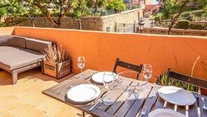 A dining table set with plates, cutlery, and wine glasses, accompanied by a sofa and a planter with plants. - Awesome apartment in Elviria with WiFi (Elviria)