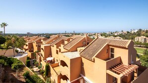 A residential area with terracotta-roofed buildings, a clear sky, and a view of the sea in the distance. - Awesome apartment in Elviria with WiFi (Elviria)