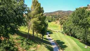 A golf course with a water hazard, trees, and a distant hill. - Awesome apartment in Elviria with WiFi (Elviria)