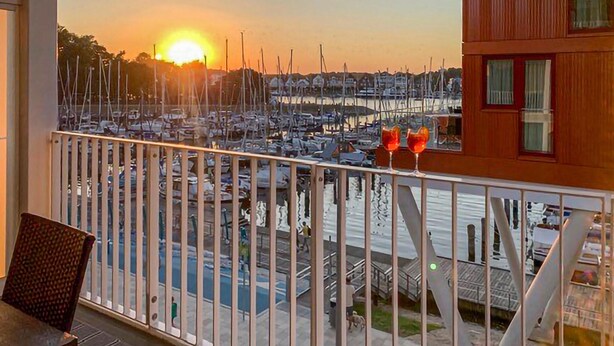 A balcony with a view of a marina at sunset. - Priwallpromenade 27, Whg 7 (Travemünde Waterfront)