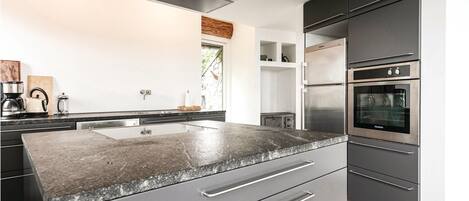 Eine moderne Küche mit Granitabdeckung, Edelstahlgeräten und einem minimalistischen Design.