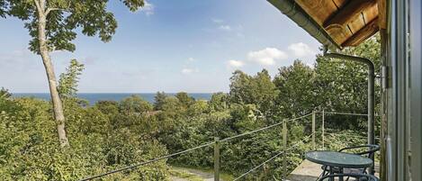A balcony with a view of the sea, surrounded by trees and vegetation.