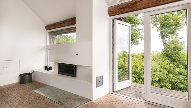 Eine moderne Küche mit Einbauofen, einem Fenster und einer Glastür, die auf einen Balkon mit Grünblick führt.