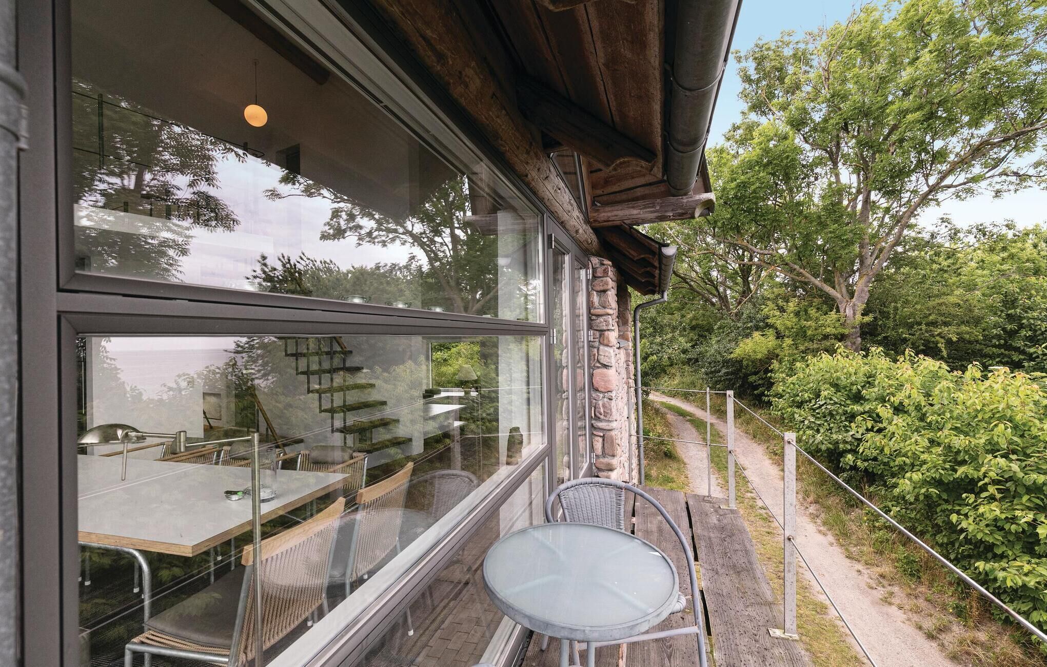 Un bâtiment moderne doté de grandes fenêtres, d’une façade en pierre et d’un patio aménagé avec des sièges extérieurs.