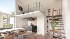 Eine moderne Loft-Wohnung mit Essbereich, Küche und Schlafgalerie, die über eine Treppe erreichbar ist.