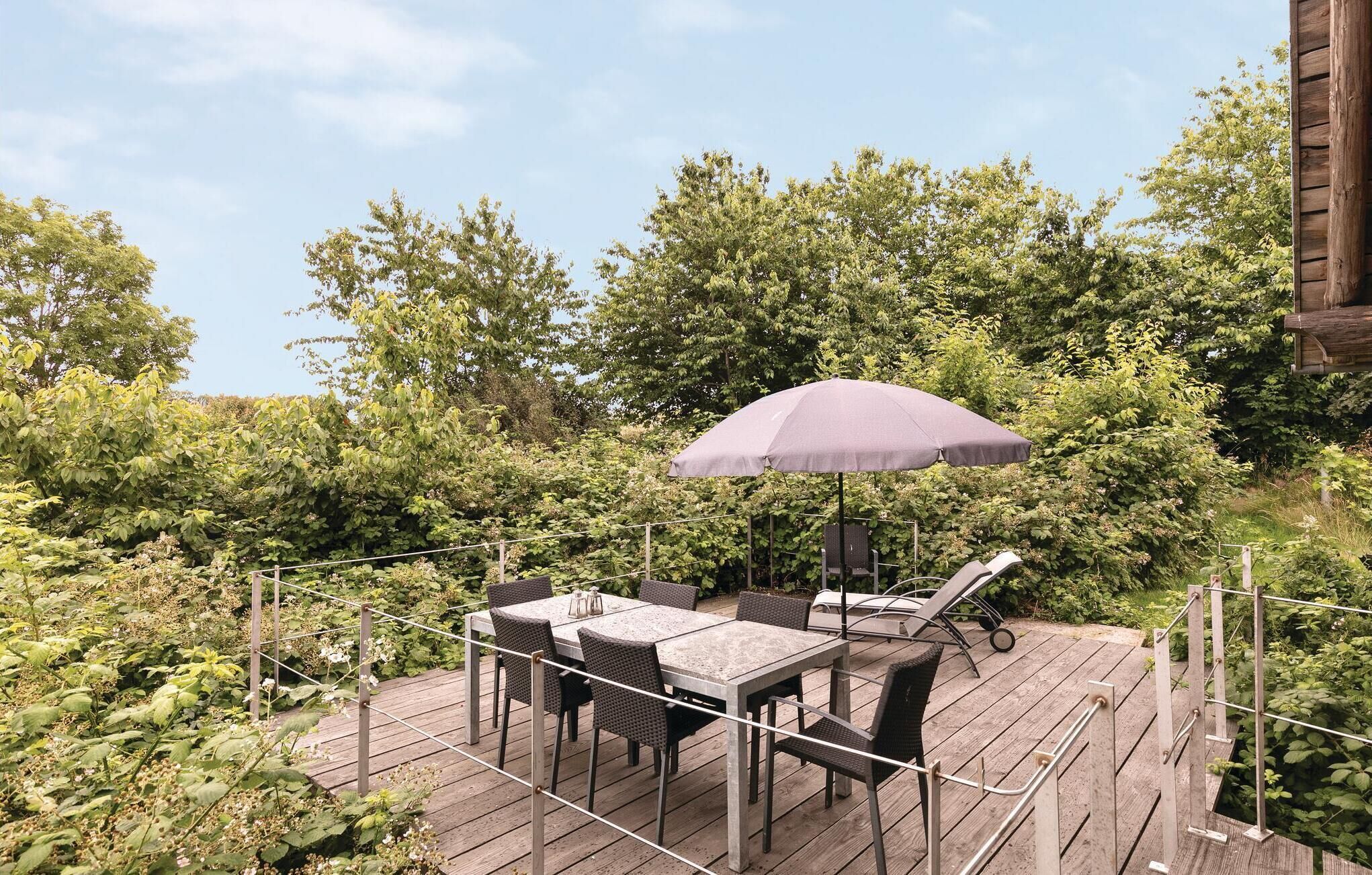 An outdoor deck with a table and chairs, surrounded by lush greenery.