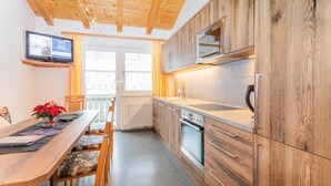 A modern kitchen with wooden cabinets, a built-in oven, and a large window.