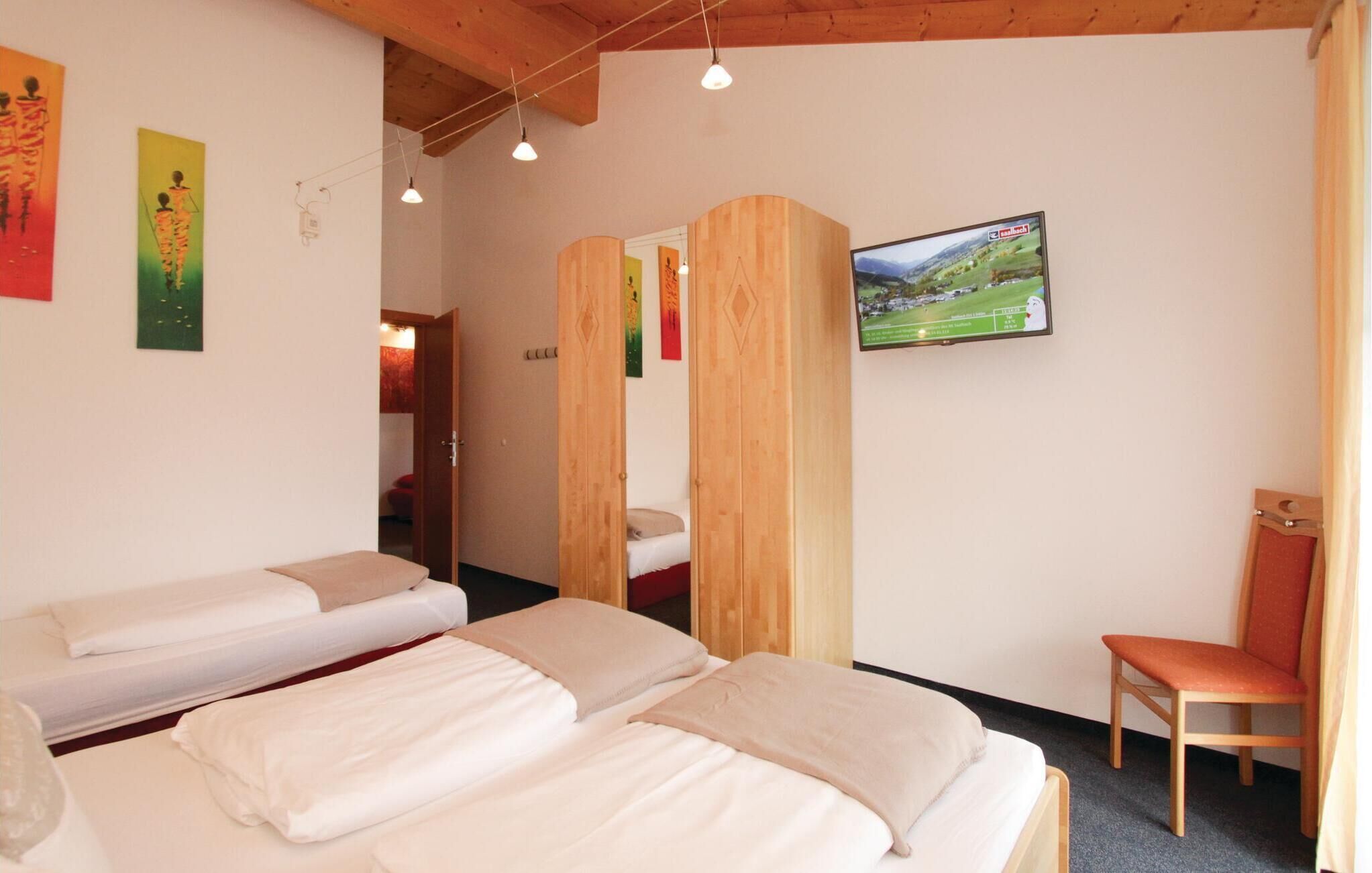 Camera d'albergo con due letti, una televisione e un armadio in legno.