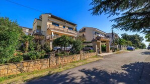 Una calle residencial con casas, muros de piedra y coches aparcados.