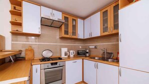 Una cocina compacta con armarios blancos y de madera, un microondas, un hervidor y una estufa.