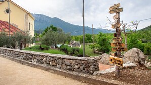 Un mur de pierre surmonté d’un panneau indicateur en bois indiquant les distances vers différents lieux.