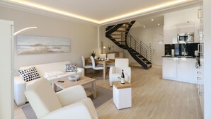 A modern living room with a white sofa, a dining area, and a kitchen. - Pet friendly apartment in Binz with WiFi (Prora/Rügen)